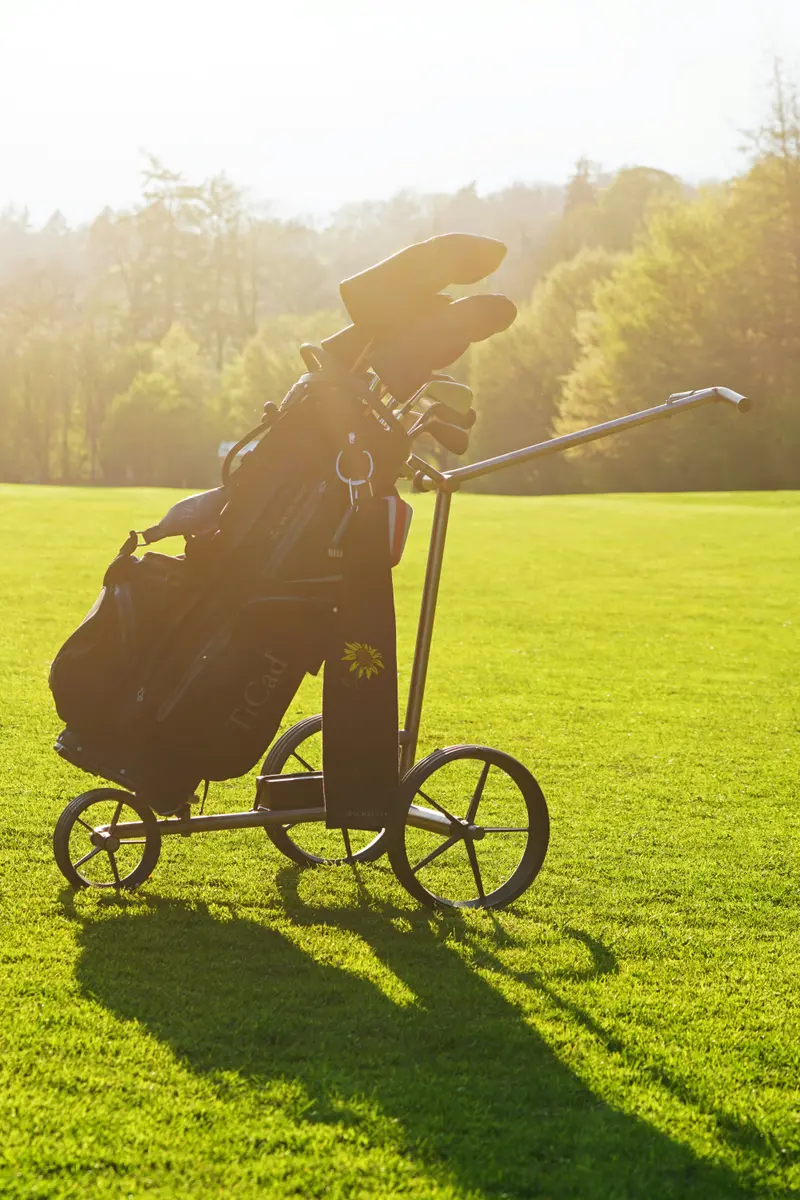 A golf course showing a golfer walking with a push cart on a beautiful sunny day